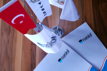 Two boxes with Nasiol logo, Turkish, Tysk, and Nasiol flag stand on the brown wooden surface