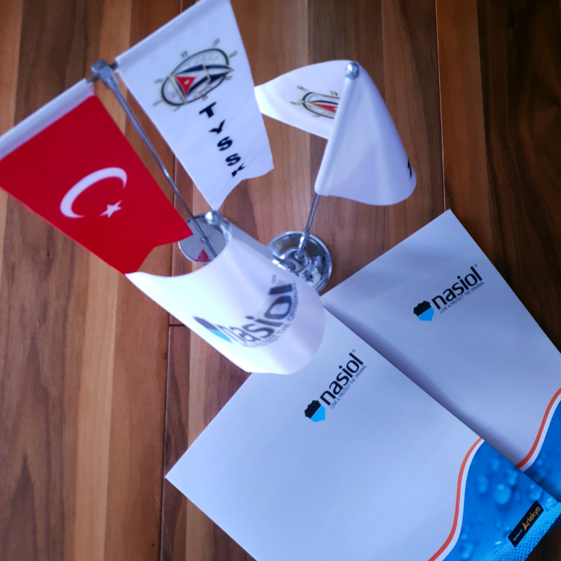 Two boxes with Nasiol logo, Turkish, Tysk, and Nasiol flag stand on the brown wooden surface
